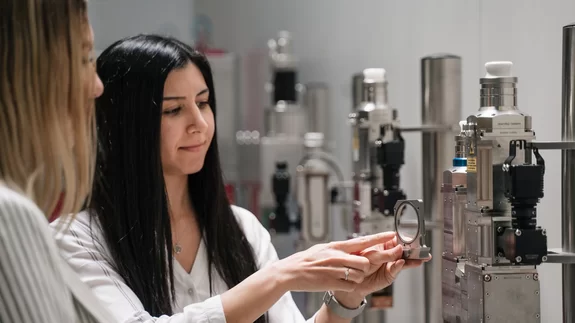 Employees explaining the function of optics in front of a display of different optics by Laserline diode lasers